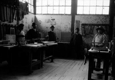 Empresarios y obreros en el interior de una "fábrica de cajas de cartón", retrato de grupo