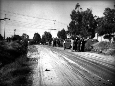 Agentes de Ministerio Público y otros hombres en una carretera durante un crímen
