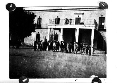 Ingenieros topógrafos y trabajadores con equipo frente a un edificio, reproducción fotográfica