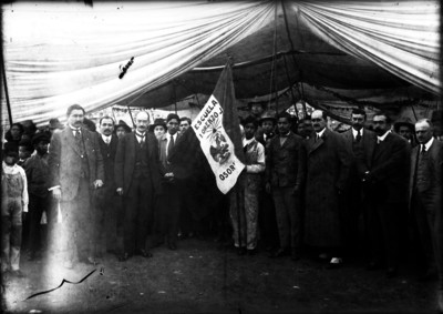 Carlos B. Zetina y otras personas sostienen la bandera de la escuela Lorenzo J. Osorio, retrato de grupo