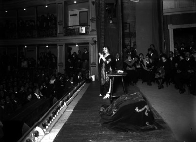 Mujer da un discurso en un teatro