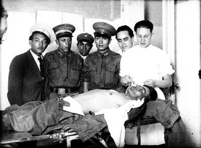 Polícias observando a un doctor mientras efectua una necropsia